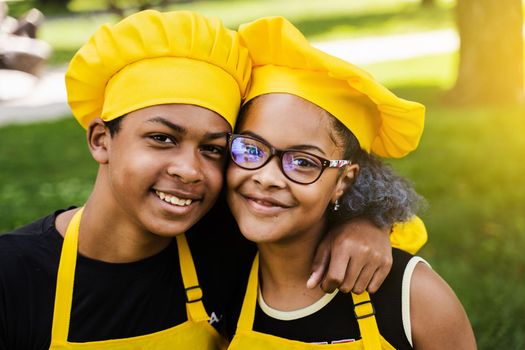 African children cooks in chefs hat and yellow uniforms smiling close-up portrait . African teenager and black girl have fun and cook food