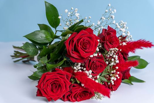 a beautiful bouquet of fresh red roses on a light blue background. Congratulations on Mother's Day. valentine's day. wedding