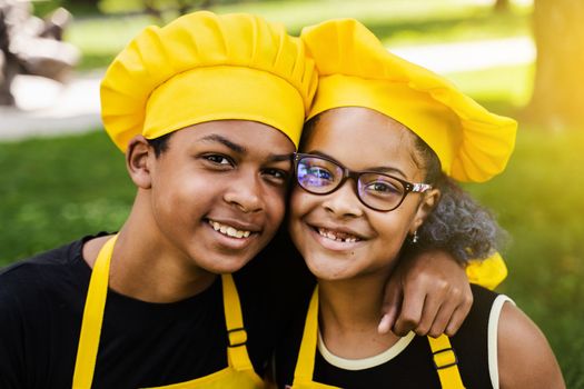 African children cooks in chefs hat and yellow uniforms smiling close-up portrait . African teenager and black girl have fun and cook food