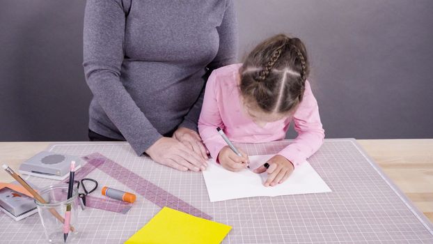 Little girl making a handmade Father's Day card from construction paper.