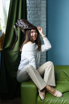 close-up photo of a brown leather bag on a womans had. indoor photo. beautiful girl in a white blouse having fun with a handbag