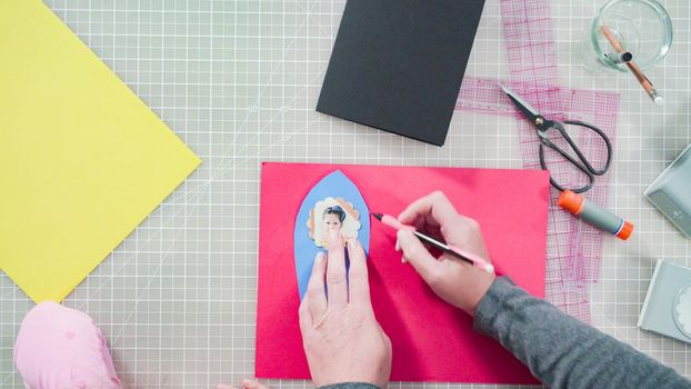 Flat lay. Little girl making a handmade Father's Day card from construction paper.