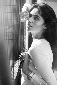 Close-up portrait of woman a in a white blause near a metal grid.