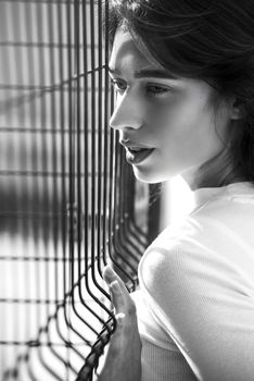 Close-up portrait of woman a in a white blause near a metal grid.