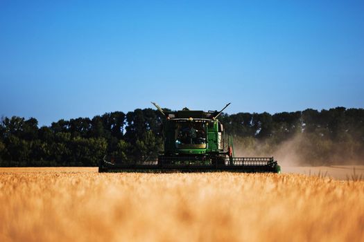 John Deere harvester works in the field. Combine Harvesting Wheat. Field field of cereals during harvesting. Modern equipment works. 07.07.22, Rostov region, Russia.