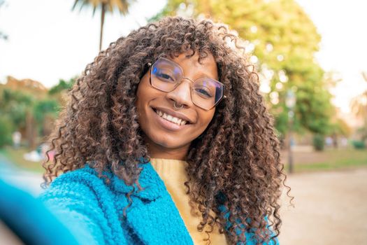 Beautiful African American woman smiling taking selfie. Positive cheerful trendy girl posing for sharing in social media app.
