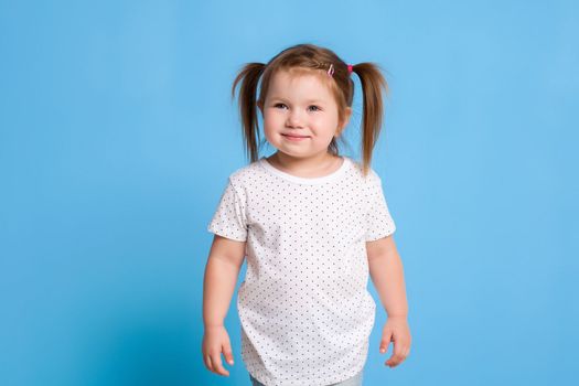 Funny kid in white T-shirt on blue background. Little pretty girl Copy space for text. Sale, birthday party concept.