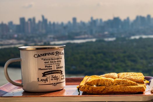 Breakfast - sandwiches and coffee on a wooden tray with natural views.