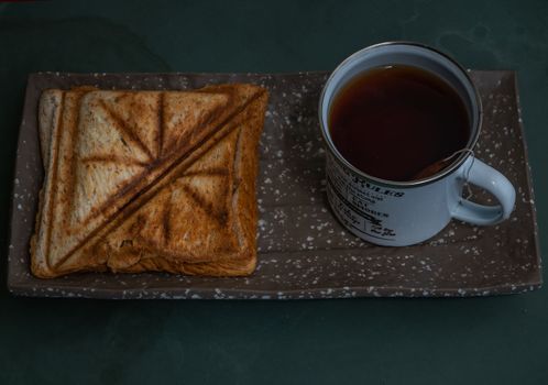 Breakfast - sandwiches and Cup of tea on a ceramics salver. Oblique view from the top.