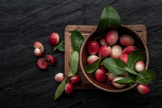 Bengal-Currants, Carandas-plum or Karonda fruit (Carissa carandas L.) sour taste fruit in Wooden cup on wicker. Top view.