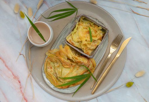 Homemade sweet frying roti (Cannabis Pancake) with Cannabis served with Cannabis tea on ceramic tray. Concept of food with cannabis herb, Treatment of medical marijuana for use in food, Top view, Selective focus.