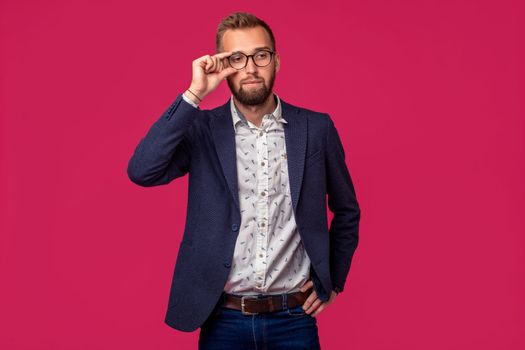 Studio shot of attractive brunette business man with glasses, in casual shirt, stylish black jacket. Isolated pink background.