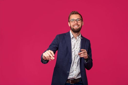 Studio shot of attractive brunette business man with glasses, in casual shirt, stylish black jacket talking, smiling. Isolated pink background.