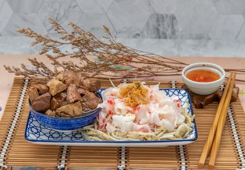 Chinese steamed rice noodles and bean sprout serve with Braised pork, Tofu, Crisp squid in sweet soy sauce in ceramic plate with pickled chili. Asian food style, Copy space, Selective focus.