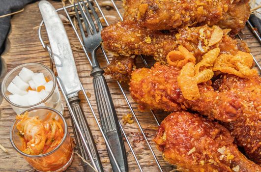 Close-up of Deep fried chicken drumstick or Crispy fried chicken legs with sesame seeds in garlic sauce in korean style serve with kimchi and pickled radish. Asian food concept, Selective focus.