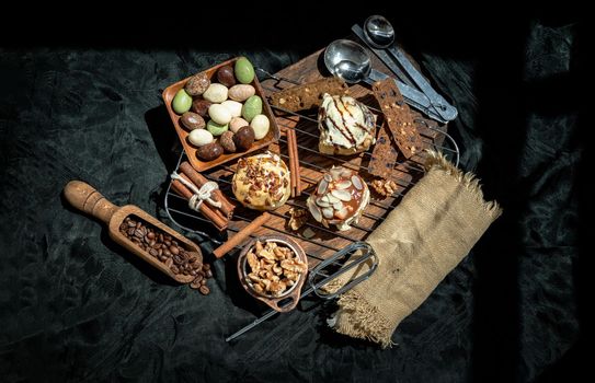 Chocobon (Soft Chocolate Bun) topped with rich cream cheese frosting, Caramel Pecan Cinnamon Roll topped with decadent caramel frosting and pecans and Thai milk tea Almond Minibon with ingredients on dark background. Top view, Copy space, Selective focus.