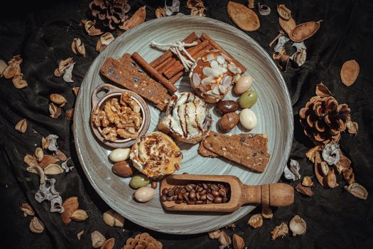 Bakery, Stick cookies, Walnuts, Roasted coffee beans and Colored eggs with Pine cones on Ceramic plate. Easter desserts, Selective focus.