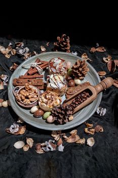 Easter bakery, Stick cookies, Walnuts and Colored eggs
with Pine cones on Ceramic plate with Dark background. Copy space, Selective focus.
