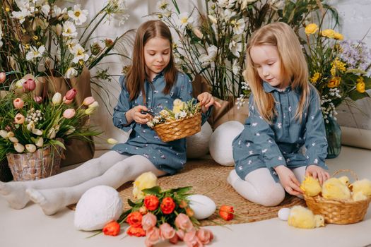 Two girls in a beautiful Easter photo zone with flowers, eggs, chickens and Easter bunnies. Happy Easter holiday