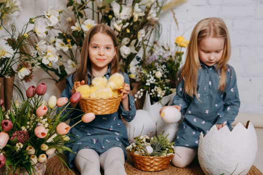 Two girls in a beautiful Easter photo zone with flowers, eggs, chickens and Easter bunnies. Happy Easter holiday