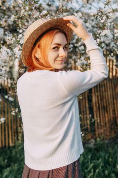 Portrait of a woman in a straw hat in a cherry blossom. Free outdoor recreation, spring blooming garden.