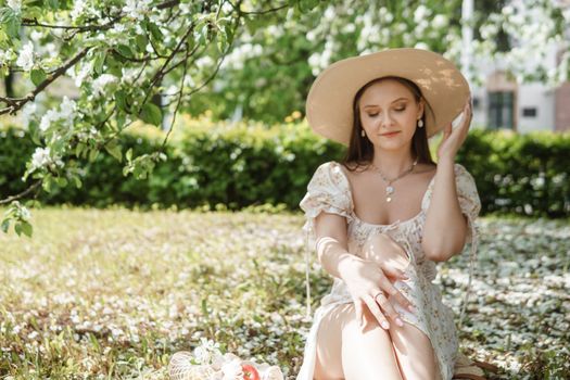 An attractive long-haired woman walks in the spring in the park of blooming apple trees. Spring portrait of a woman