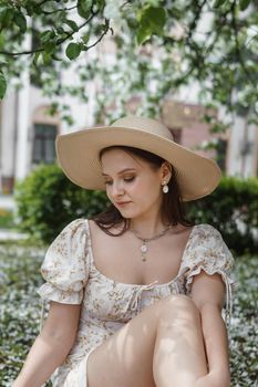 An attractive long-haired woman walks in the spring in the park of blooming apple trees. Spring portrait of a woman