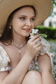 An attractive long-haired woman walks in the spring in the park of blooming apple trees. Spring portrait of a woman
