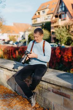 Man Sitting on Stairs in Old European City And Holding Photo Camera. Contemporary Stylish Blogger And Photographer