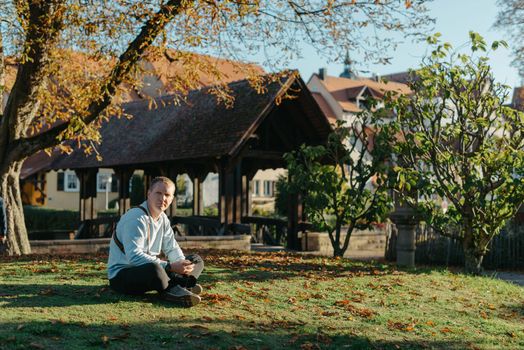 Professional photographer taking picture of beautiful autumn park. man professional photographer sit with camera in autumn park