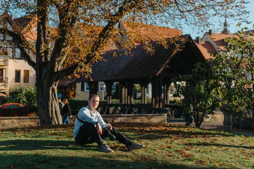 Professional photographer taking picture of beautiful autumn park. man professional photographer sit with camera in autumn park