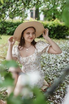 An attractive long-haired woman walks in the spring in the park of blooming apple trees. Spring portrait of a woman