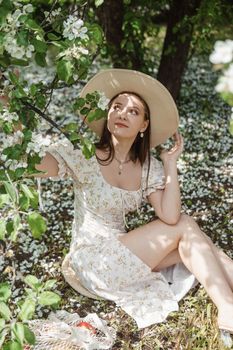 An attractive long-haired woman walks in the spring in the park of blooming apple trees. Spring portrait of a woman