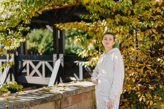 Beautiful elegant woman standing in a park in autumn. autumn yellow leaves. Portrait of joyful woman in park during fall. Happy girl with yellow leaves outdoor. Beauty Romantic Girl Outdoors enjoying nature. Beautiful autumn model with waving glow hair.Sun light on sunset.Warm toned art work. Portrait of romantic female