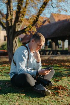 Professional photographer taking picture of beautiful autumn park. man professional photographer sit with camera in autumn park