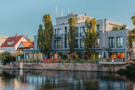 River on sunset. Townhouses buildings and multi-floor home at waterfront. Sunset on River in city. Suburb houses and residential building near river in Europe. House in nature on shore on sunset.