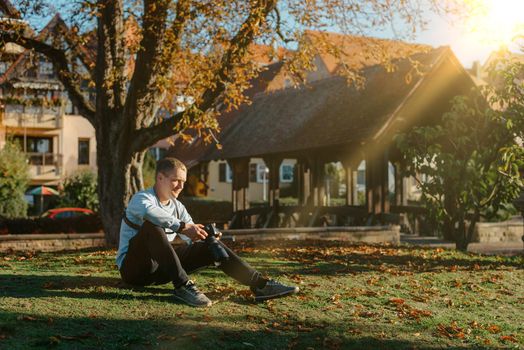 Professional photographer taking picture of beautiful autumn park. man professional photographer sit with camera in autumn park