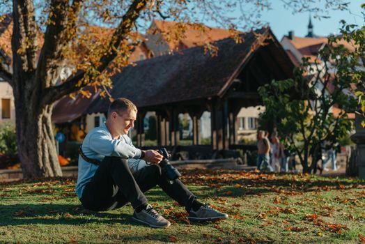 Professional photographer taking picture of beautiful autumn park. man professional photographer sit with camera in autumn park