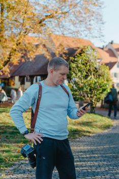 Professional photographer taking picture of beautiful autumn park. man professional photographer sit with camera in autumn park