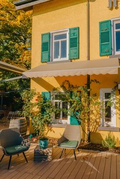 Image of a empty coffee tables arranged in backyard of a house. Autumn in Germany, Europe. Outdoor table in street cafe. autumn outdoor cafe wooden furniture old europe. Autumn photo of old-fashioned cozy and empty outdoor cafe with wooden furniture in a European town. Cafe concept