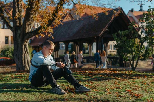 Professional photographer taking picture of beautiful autumn park. man professional photographer sit with camera in autumn park