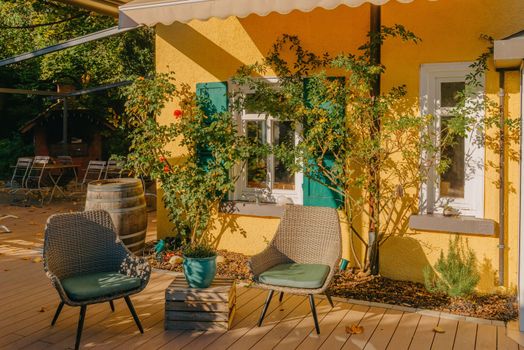 Image of a empty coffee tables arranged in backyard of a house. Autumn in Germany, Europe. Outdoor table in street cafe. autumn outdoor cafe wooden furniture old europe. Autumn photo of old-fashioned cozy and empty outdoor cafe with wooden furniture in a European town. Cafe concept