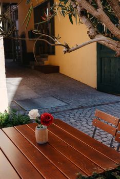 Empty cafe terrace with white table and chair. exterior of the cafe restaurant. interior Street cafe. Cozy street with flowers and French-style cafe table. Decor facade of coffeehouse with bike. Table on a summer terrace with cake and teapot. Garden table and chairs