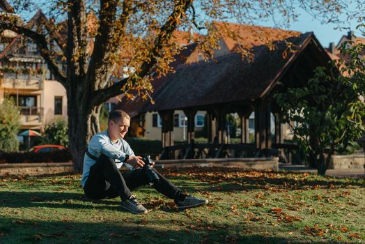 Professional photographer taking picture of beautiful autumn park. man professional photographer sit with camera in autumn park