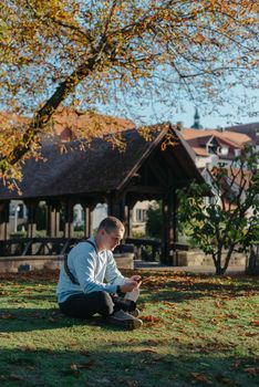 Professional photographer taking picture of beautiful autumn park. man professional photographer sit with camera in autumn park
