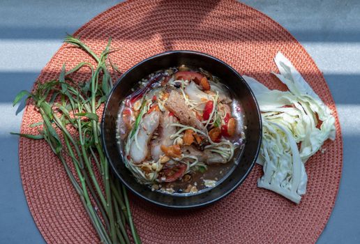 Thai papaya spicy salad (som tum) mix grilled pork neck on ceramic dishes. delicious spicy Thai food, Selective focus.