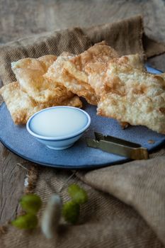 Homemade Sweet Crispy Thai Roti (Thai Pancake) Served with Sweetened condensed milk on ceramic plate. Delicious Thai Dessert, Selective focus.