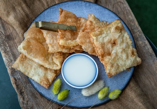 Homemade Sweet Crispy Thai Roti (Thai Pancake) Served with Sweetened condensed milk on ceramic plate. Delicious Thai Dessert, Selective focus.