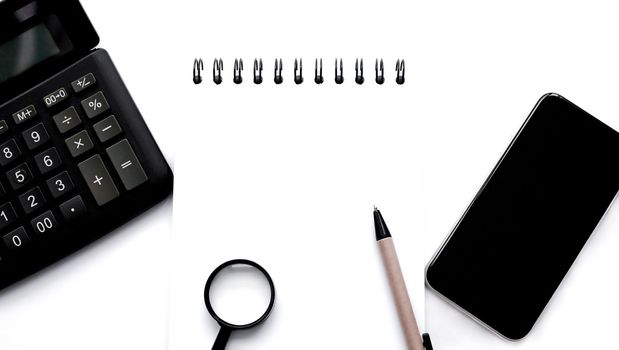 calculator, spiral notebook, notepad, magnifying glass, pen and smartphone on white background