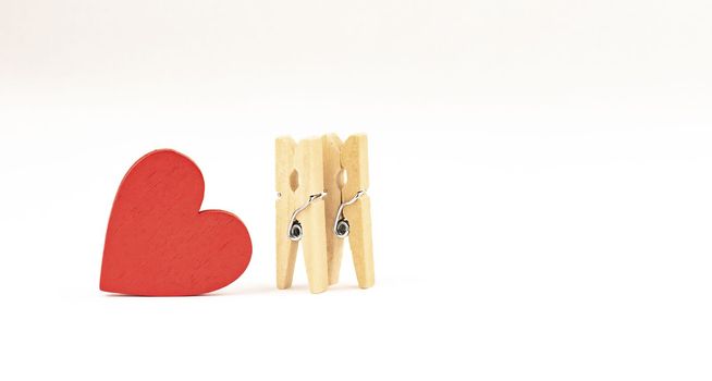 concept composition of love relationships outstanding. two clothespins and red wooden heart.